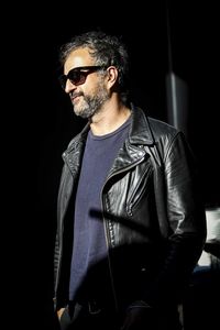 Young man wearing sunglasses standing against black background