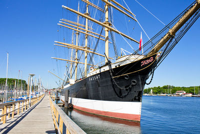 Ship moored at harbor against clear blue sky
