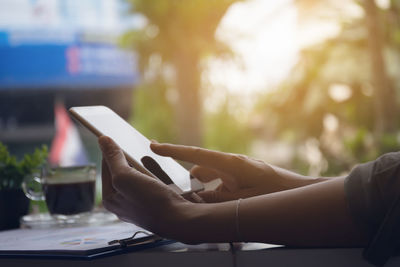 Midsection of man using mobile phone on table