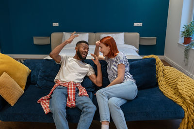 Humour in relationships. happy joyful interracial couple sit on sofa and laughing together