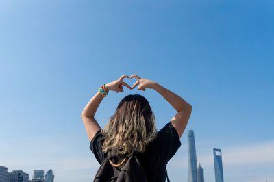 Rear view of woman with umbrella against clear blue sky