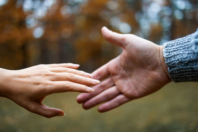 The hands of a man and a woman reach each other.