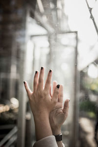 Cropped hand of woman by glass window