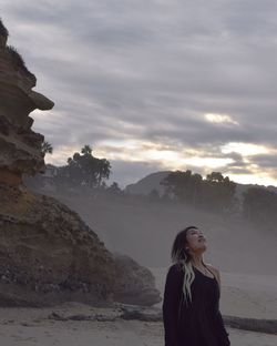 Young woman looking at sea against mountain range