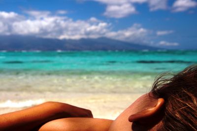 Midsection of woman at beach against sky