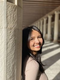 Portrait of young woman standing against stone wall