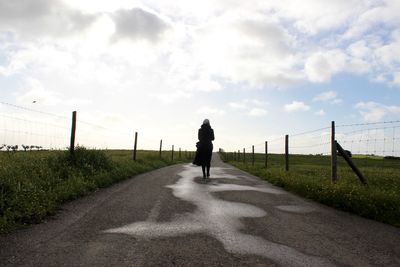 Rear view of man walking on road