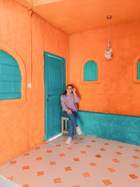Full length of woman sitting on wall