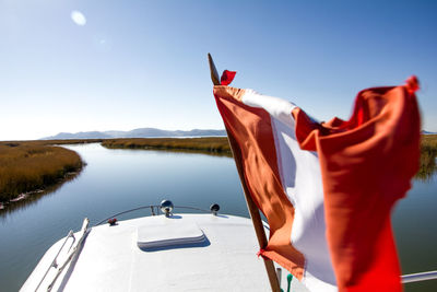 Close-up of flag on boat at river against sky