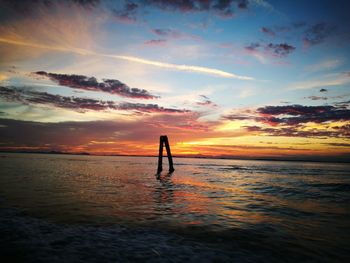 Silhouette man standing on beach against sky during sunset
