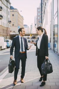 Happy business people standing and talking on sidewalk