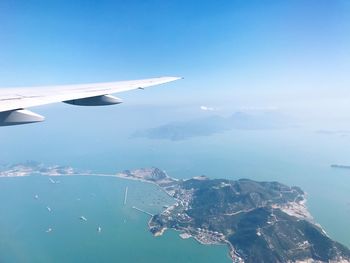 Aerial view of airplane flying over sea against sky