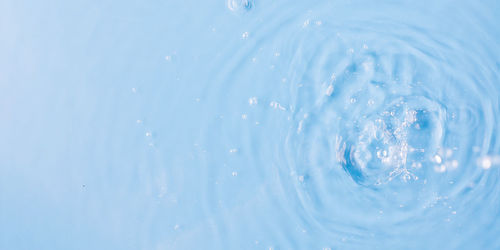 Pouring and splashing clear water on light blue background upper close view