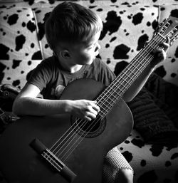 High angle view of boy playing guitar at home