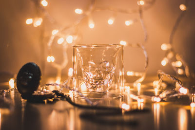Close-up of glass with illuminated string lights on table