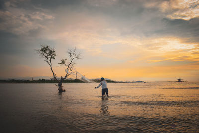 Man on beach against sky during sunset