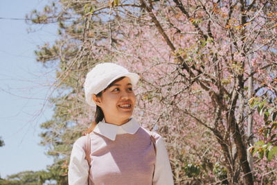 Smiling young woman wearing cap while looking away at park