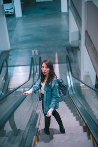 Portrait of smiling young woman standing on railing