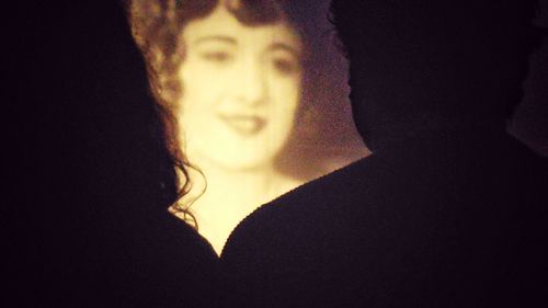 Close-up of woman against black background