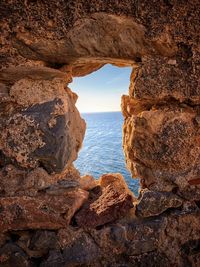 Rock formation on sea shore against sky