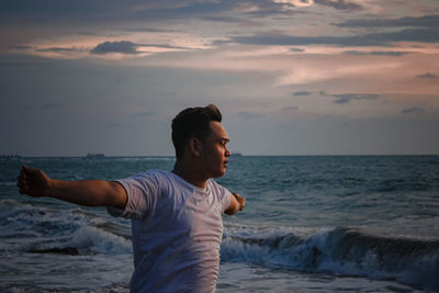 Man standing on beach against sky during sunset