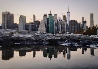 Reflection of city on lake against sky