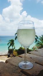 Close-up of beer glass on beach against sky