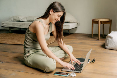 Young woman using mobile phone while sitting on sofa at home