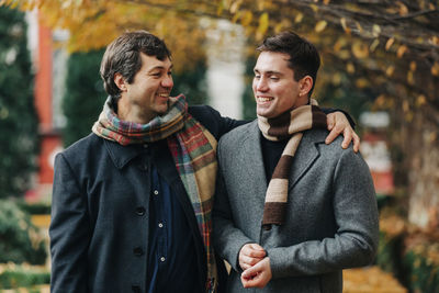 Smiling man with arm around adult son