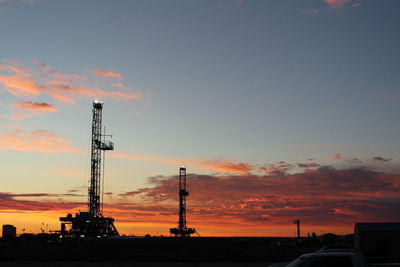 Low angle view of silhouette factory against sky during sunset