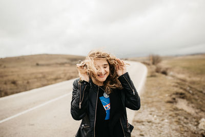 Portrait of young woman standing against the sky