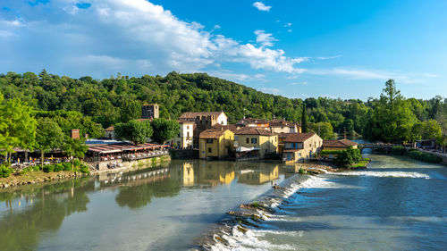 Buildings by river against sky