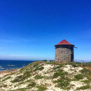 Building by sea against clear blue sky