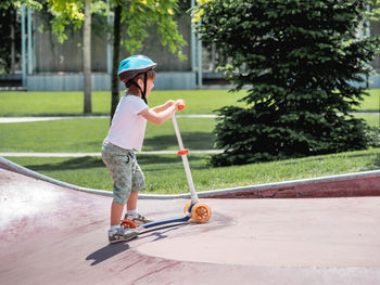 Brave boy rides kick scooter in skate park. special concrete bowl structures in urban park. 