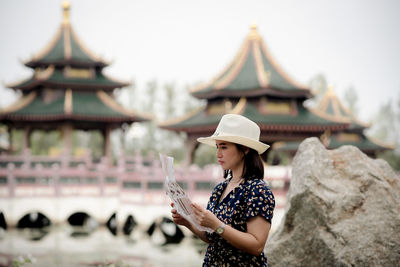 Woman holding paper while standing outdoors