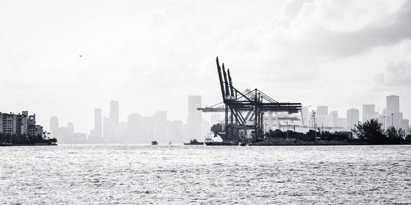 Cranes at harbor against sky