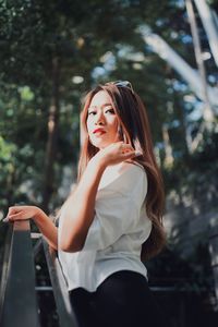 Beautiful young woman standing against tree