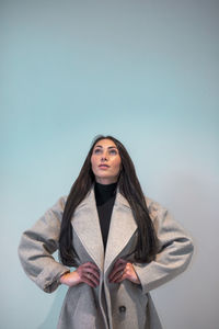 Portrait of young woman standing against wall