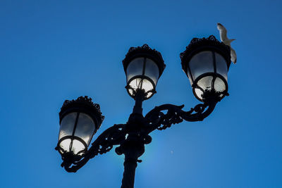 Low angle view of illuminated street light against blue sky