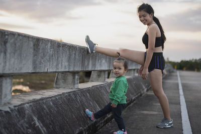 Full length of young woman standing on railing