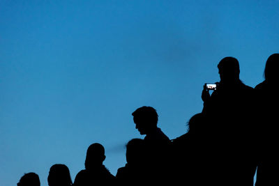 Silhouette people against blue sky