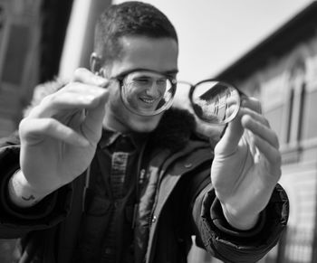 Smiling young man holding eyeglasses