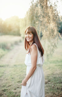 Young woman smiling while standing on field