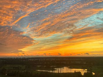 Scenic view of river against dramatic sky during sunset