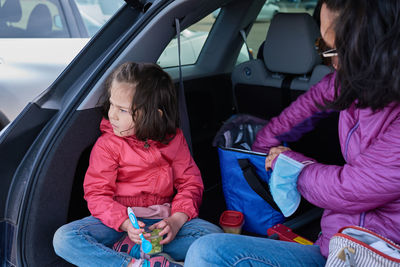 Mom and daughter having snacks in the back of an suv