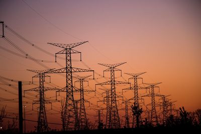 Low angle view of silhouette electricity pylon against sky