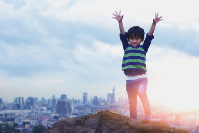 Full length of child standing by cityscape against sky