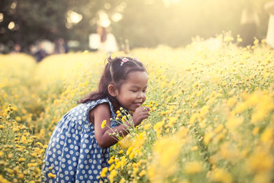 Carefree girl playing with flower on field