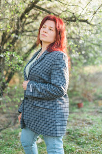 Young woman standing against trees