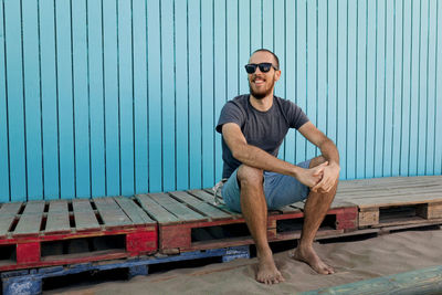 Portrait of young man sitting on wall